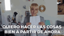 a woman is holding a piece of paper with the words quiero hacer las cosas bien a partir de ahora