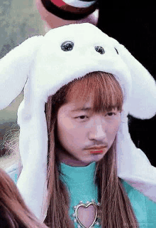 a girl wearing a bunny hat with ears and a mustache is making a funny face .