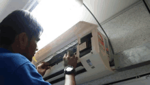 a man wearing a watch is working on an air conditioning unit