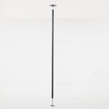 a black pole is against a white wall and has a stainless steel base