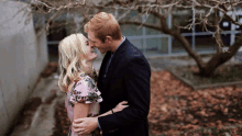 a man and woman are kissing under a tree