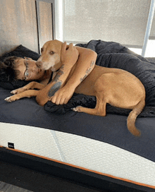 a man laying on a bed with a dog that has a tattoo on his arm that says " i love you "