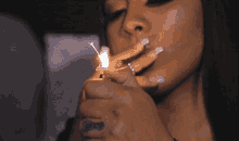 a woman is lighting a cigarette with a lighter and has a tattoo on her finger