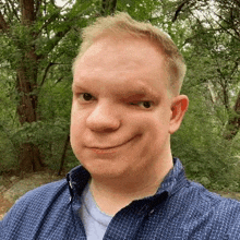 a man with a missing eye is taking a selfie in front of trees .