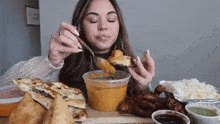 a woman is sitting at a table eating food with a sign that says i love you in the background