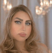 a close up of a woman 's face in front of a chandelier