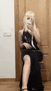 a woman in a black dress is taking a picture of herself with her phone