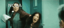 two women are fighting in a hallway with the word ncaa written on the bottom .