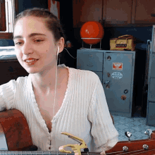 a woman playing a guitar in front of a cabinet that has a sticker on it that says ' columbia '