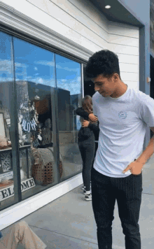 a man in a white shirt is hugging a woman in front of a store window that says " aloha "