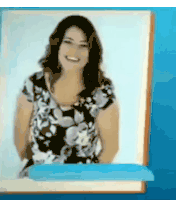 a woman in a floral dress is smiling in front of a blue wall .