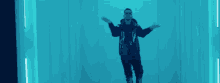 a man in a black jacket and black pants is walking in a blue room