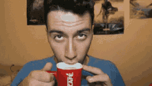 a man is drinking from a red cup that says nescafe