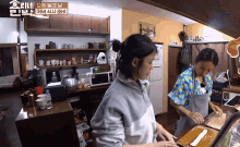 two women in aprons are preparing food in a kitchen with a sign that says ' seoul ' on it