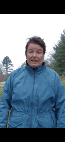 a woman wearing a blue jacket is standing in a field