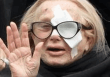 a woman wearing glasses and a bandage on her face is making a funny face .