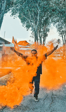 a man is surrounded by orange smoke while holding a flag