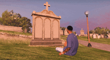 a man sits in a cemetery in front of a grave