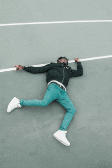 a man in a black jacket is laying on the ground with his legs crossed