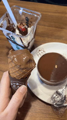 a person is holding a chocolate ice cream cone in front of a plate that says peak