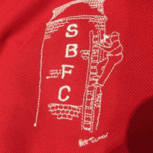 a red shirt with a white embroidered logo that says sbfc