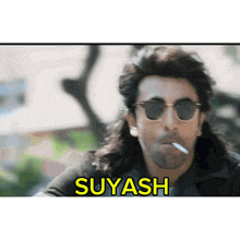 a man wearing sunglasses is smoking a cigarette and the word suyasha is on the bottom