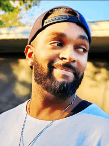 a man with a beard is wearing a hat and necklace