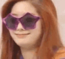 a woman wearing a pair of purple star shaped sunglasses .