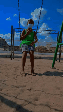 a young boy wearing a green shirt with the word jeep on it sits on a swing