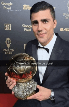 a man in a tuxedo is holding a soccer ball in front of a google pixel sign