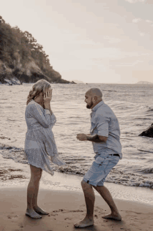 a man kneeling down to propose to a woman on a beach