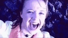 a close up of a woman screaming with her mouth open in a dark room .