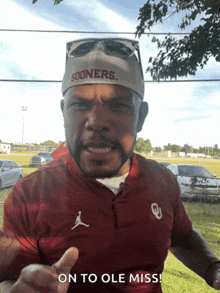 a man wearing a sooners hat and an oklahoma shirt says on to ole miss