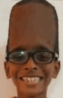 a young boy wearing glasses and a very large head is smiling .