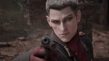 a man in a red uniform is holding a gun and pointing it at the camera .