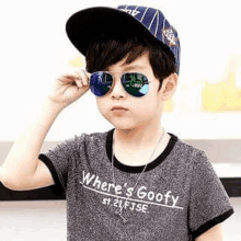 a young boy wearing a baseball cap and sunglasses .