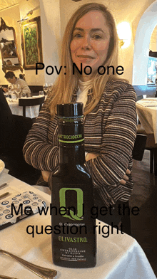 a woman sitting at a table with a bottle of olivastro olive oil