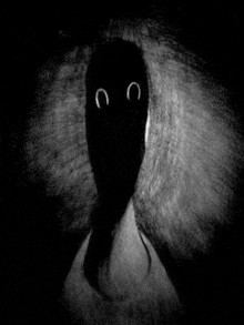 a black and white photo of a person 's shadow with glowing eyes in the dark .