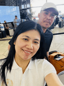 a man and a woman are posing for a photo at an airport