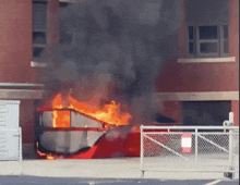 a large dumpster is burning in front of a brick building