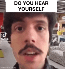 a man with a mustache is standing in front of a couch in a store and says `` do you hear yourself '' .