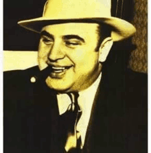 a man in a hat and tie is smoking a cigar and smiling .