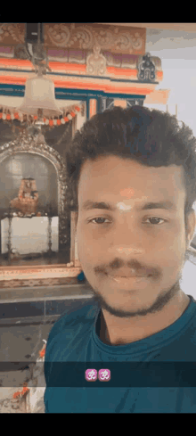 a man taking a selfie in front of a temple with a bell hanging from the ceiling