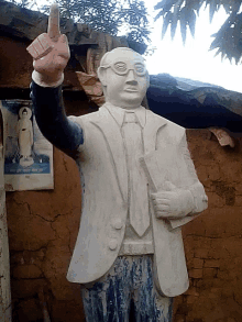 a statue of a man giving the middle finger in front of a poster of a woman