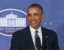 a man in a suit and tie stands in front of microphones in front of the white house in washington