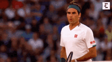 a man in a white shirt with a green headband is holding a tennis racquet in front of a crowd .