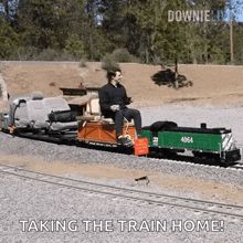 a man is sitting on the back of a train with the words " taking the train home " below him