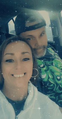 a man and a woman are posing for a picture in a car and the man is wearing a green shirt with skulls on it