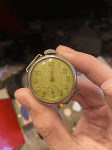 a person is holding a watch with the hands on the numbers 1 and 12