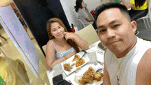 a man and a woman are sitting at a table with food